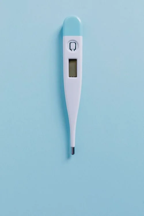 Illustrative digital thermometer on a pale blue background