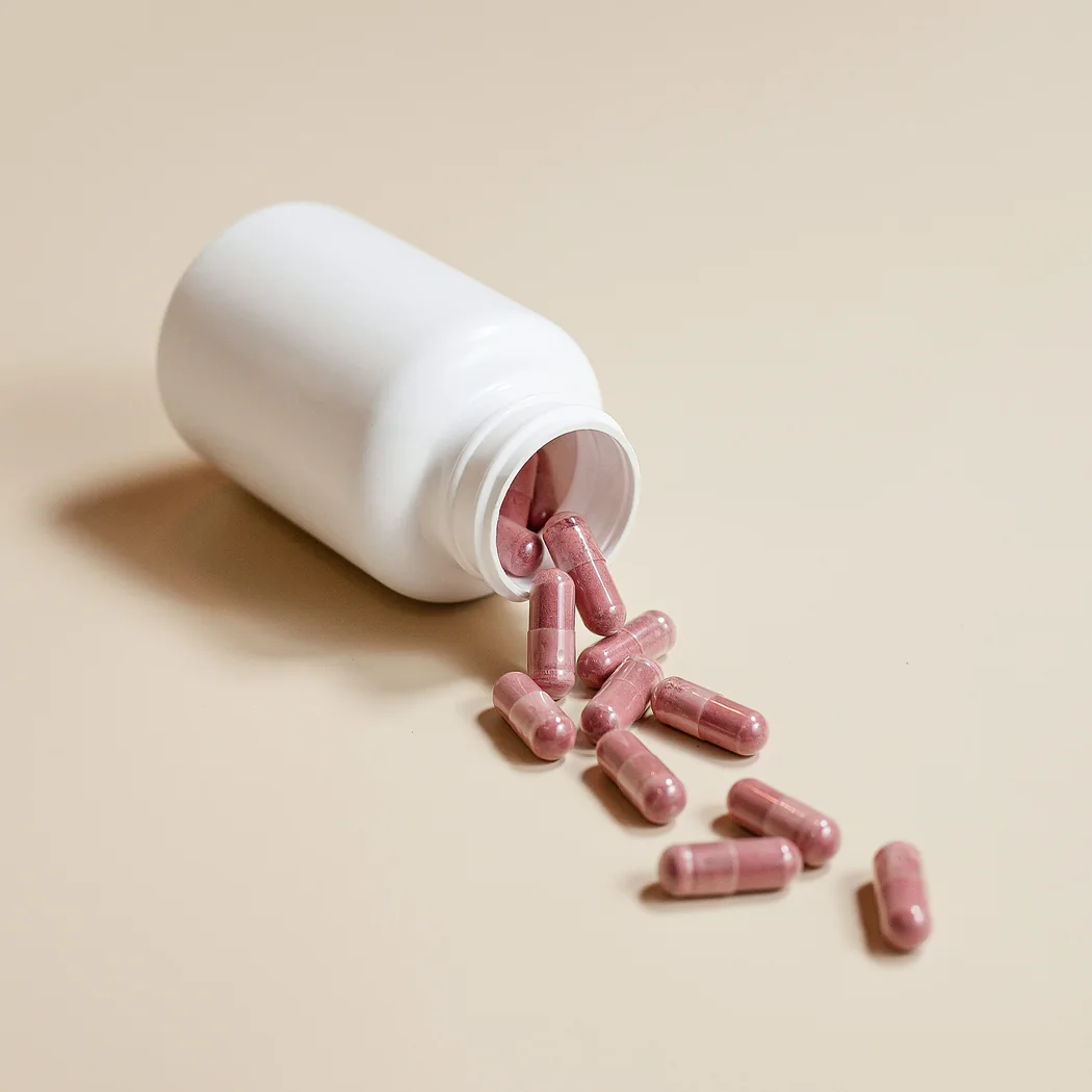 Illustrative white supplement bottle with pink capsules